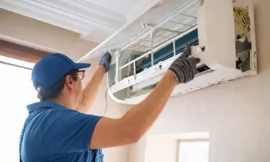 Serwisant montuje klimatyzator ścienny na ścianie.