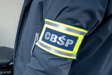 Fragment munduru funkcjonariusza z opaską oznaczoną skrótem CBŚP na ramieniu.